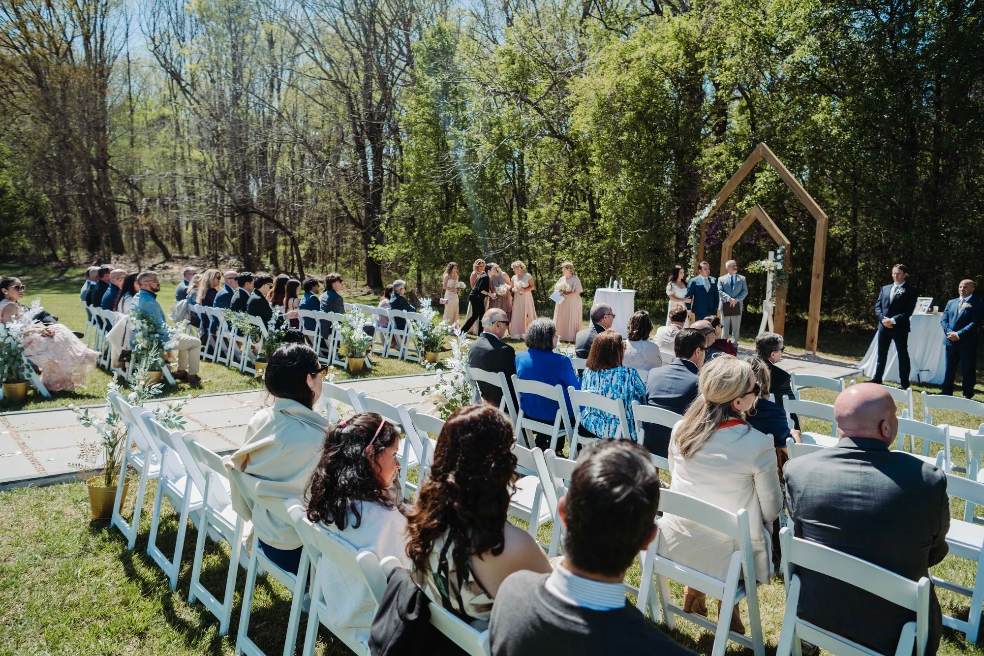Guests seated for an open-air ceremony beneath wooden arches at The Heritage Barn