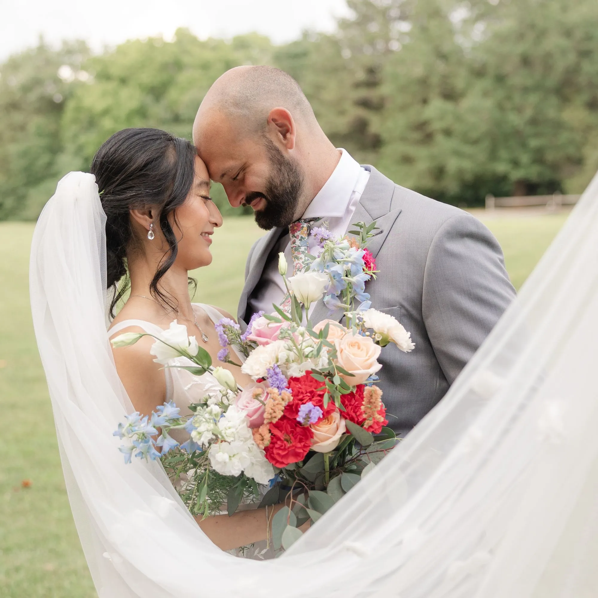 Couple touching foreheads as the bride's veil sweeps around them at The Heritage Barn