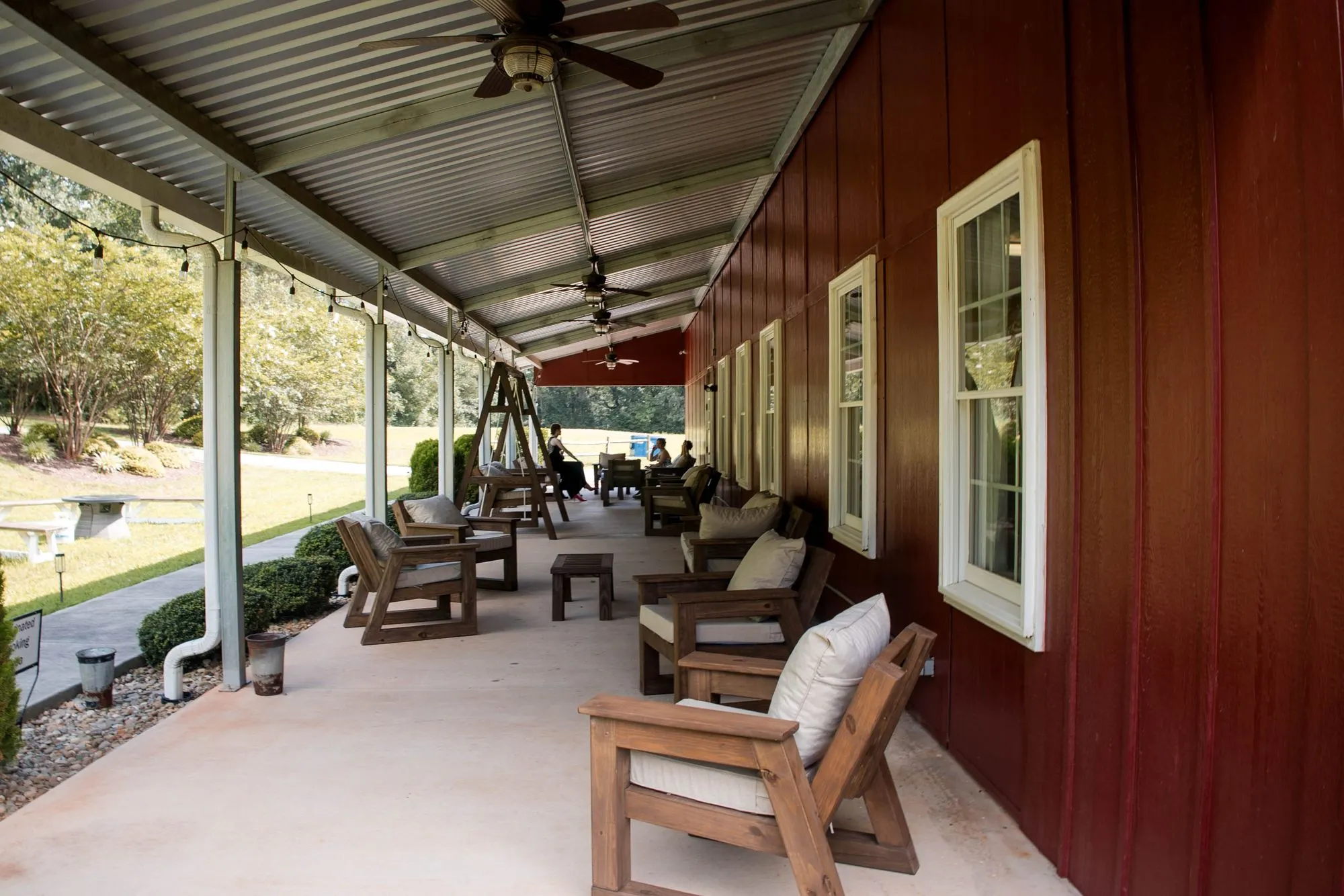 Covered patio with lounge seating along the red barn at The Heritage Barn