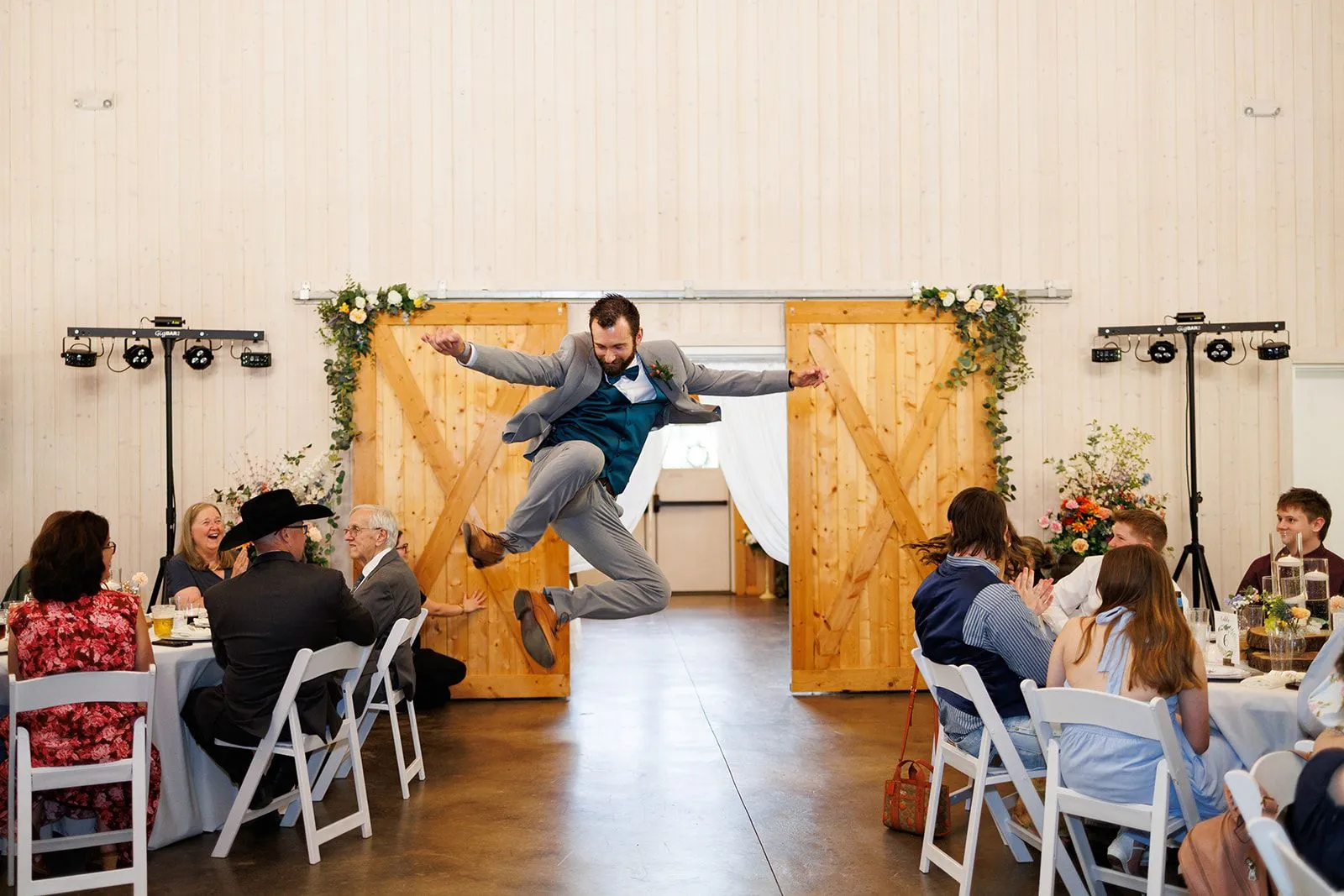 Groom leaping into the reception as guests cheer at The Heritage Barn
