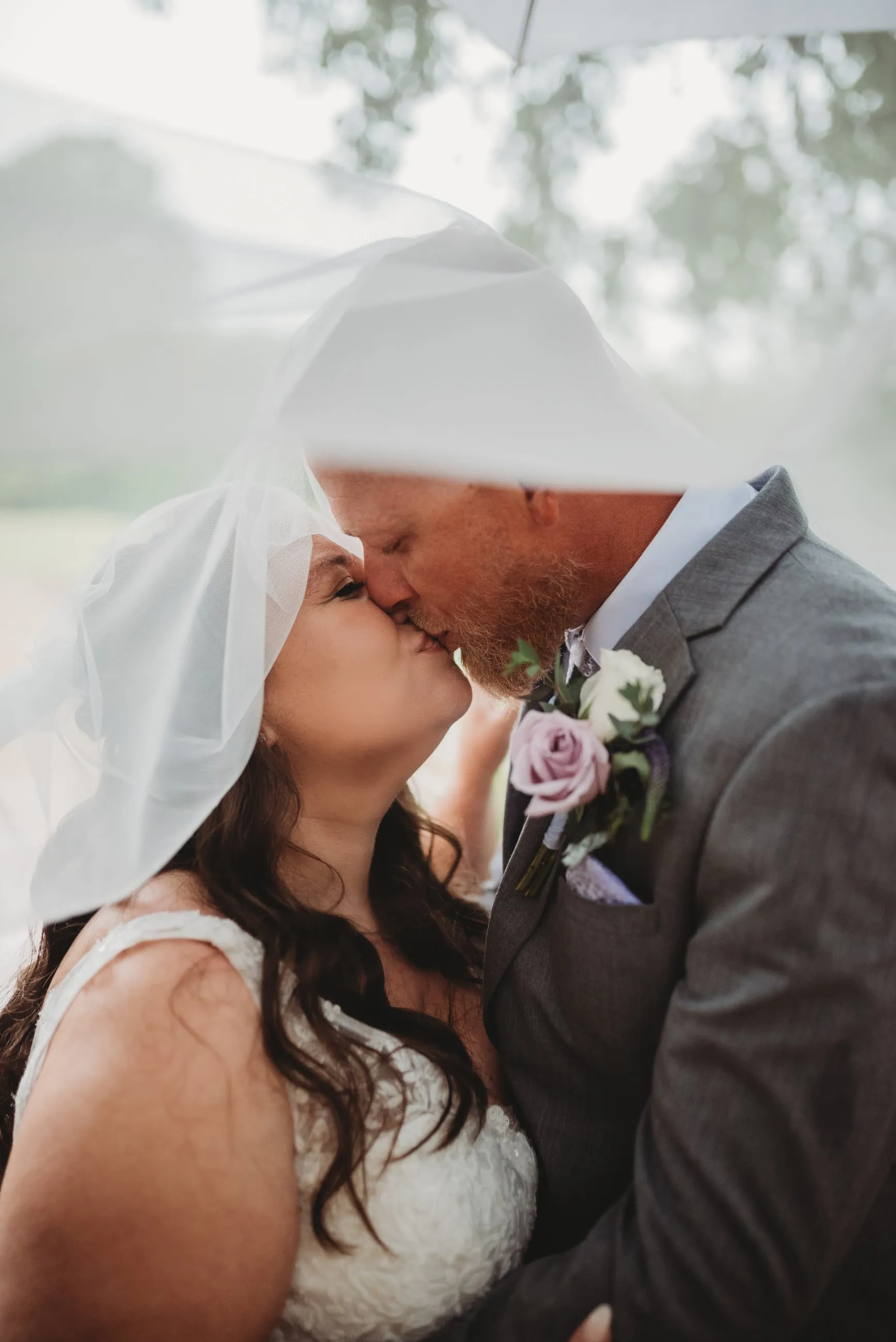 Couple kissing beneath a flowing veil at The Heritage Barn