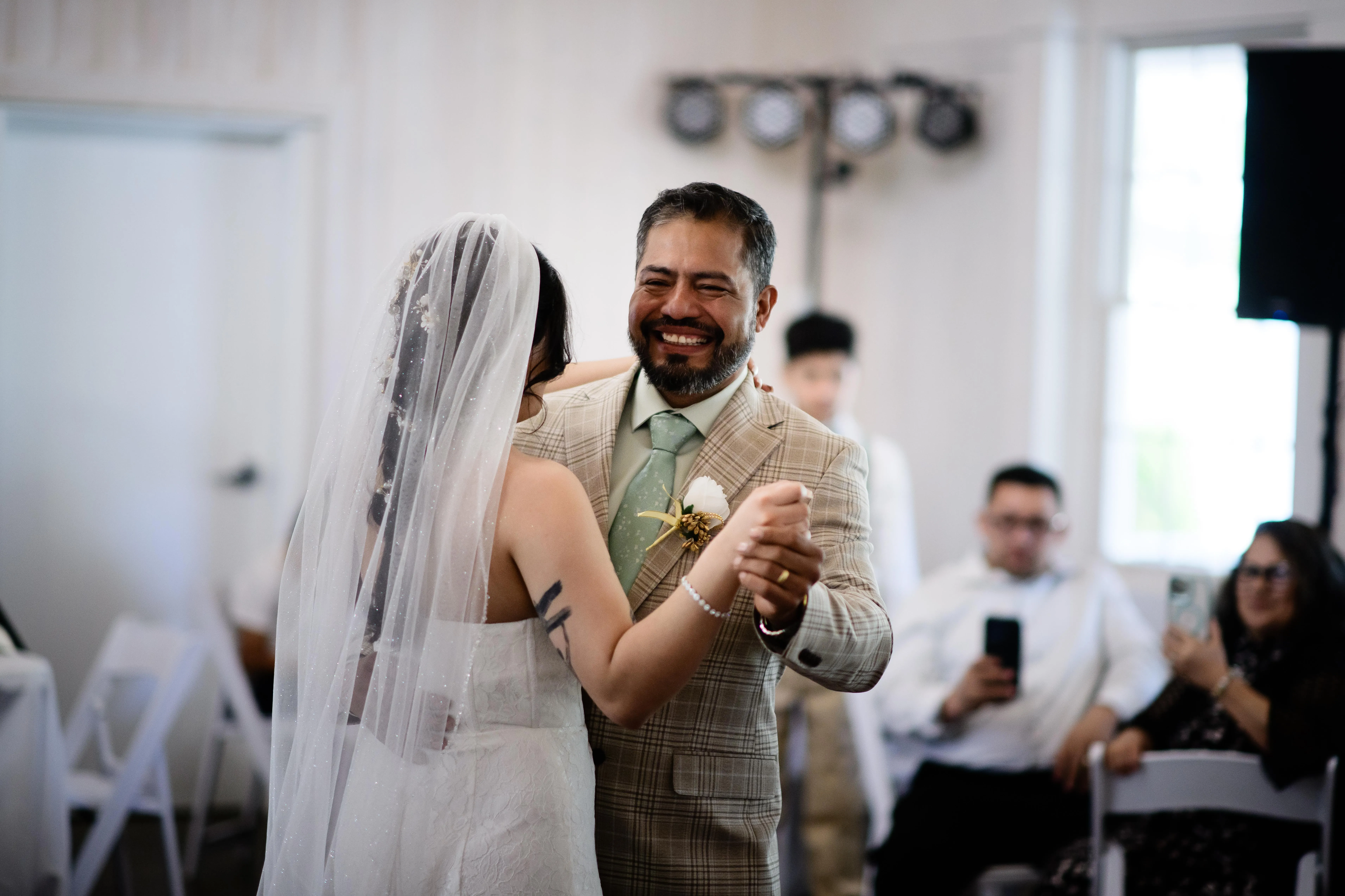 Couple sharing a first dance inside The Heritage Barn as guests look on