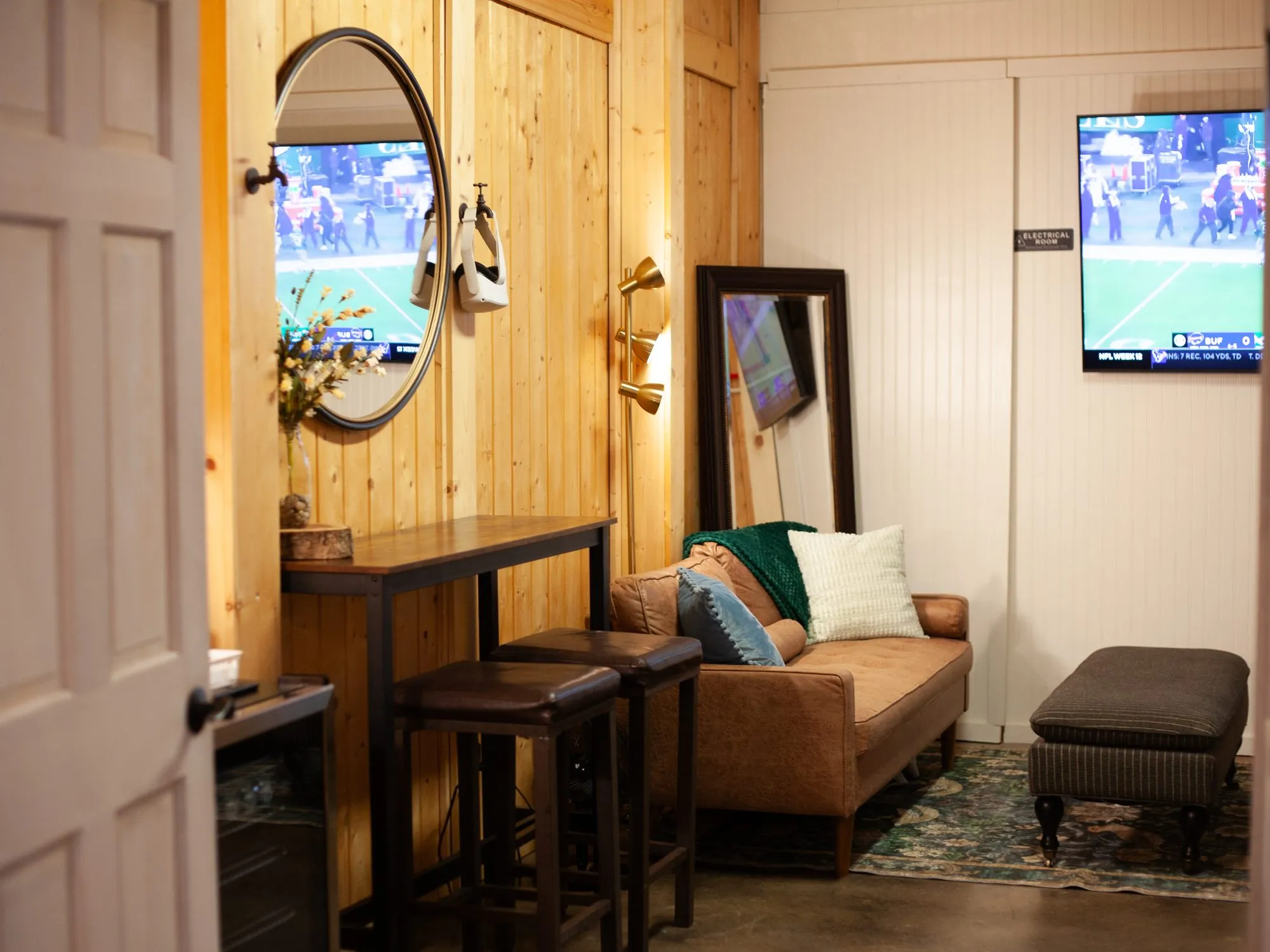 Groom's room with a leather sofa, bar-height table and TVs at The Heritage Barn