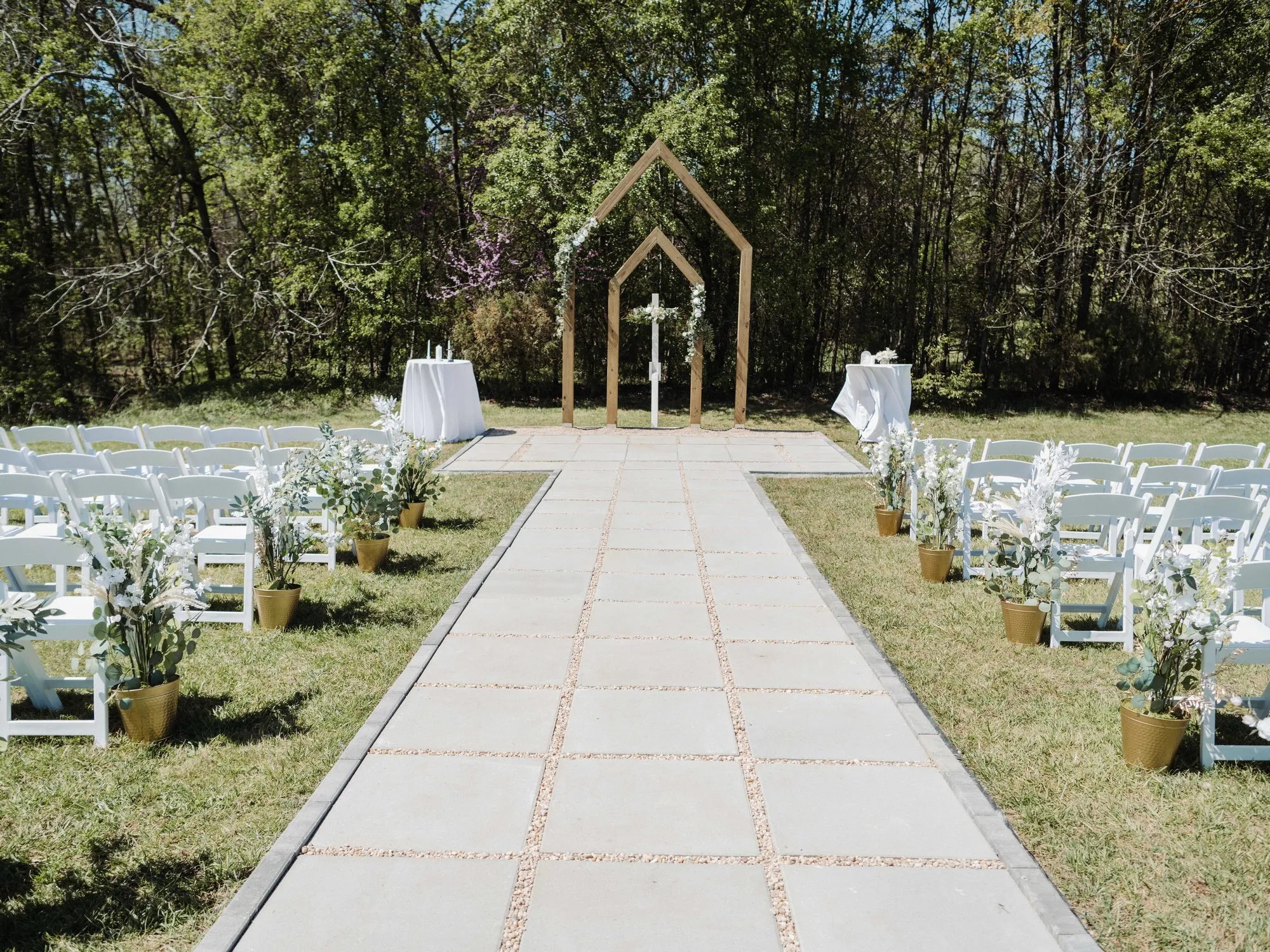 Hillside ceremony site with a stone aisle and wooden arch at The Heritage Barn